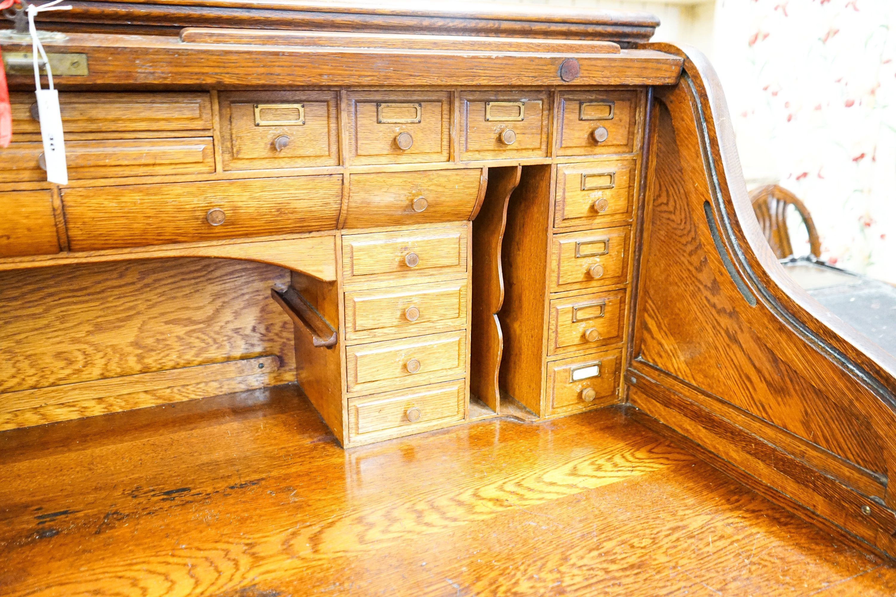 An early 20th century oak roll top desk with 'S' shape tambour, width 140cm, depth 80cm, height 128cm